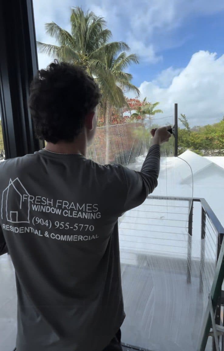 Technician cleaning a large window with a professional squeegee