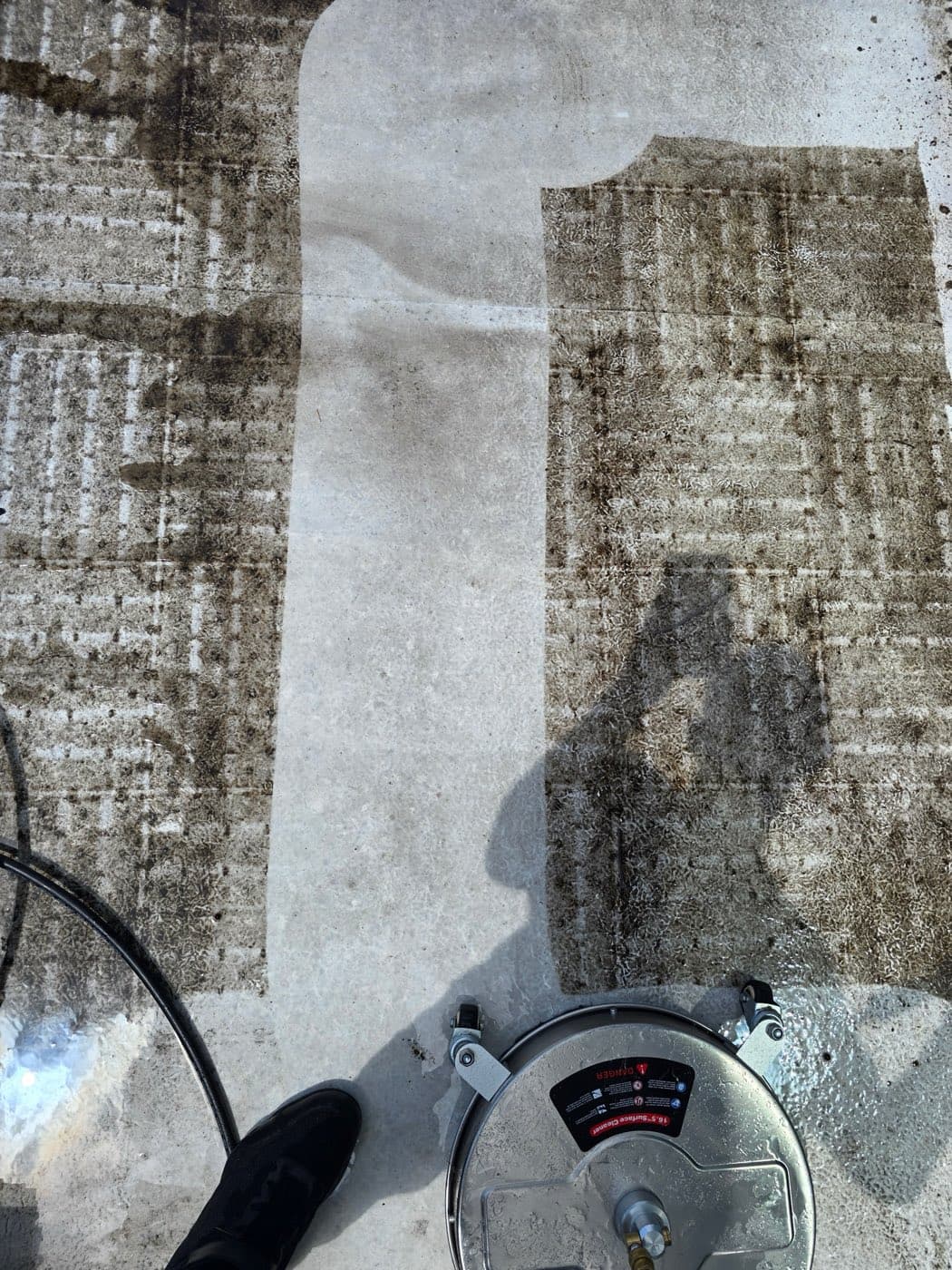 A Fresh Frames surface cleaner cutting a crisp, bright clean stripe through a grimy concrete patio in a single pass