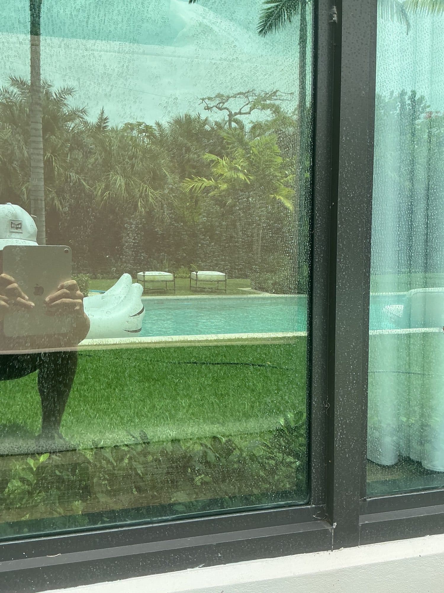 Before — hazy, hard-water-spotted window glass obscuring the backyard pool view
