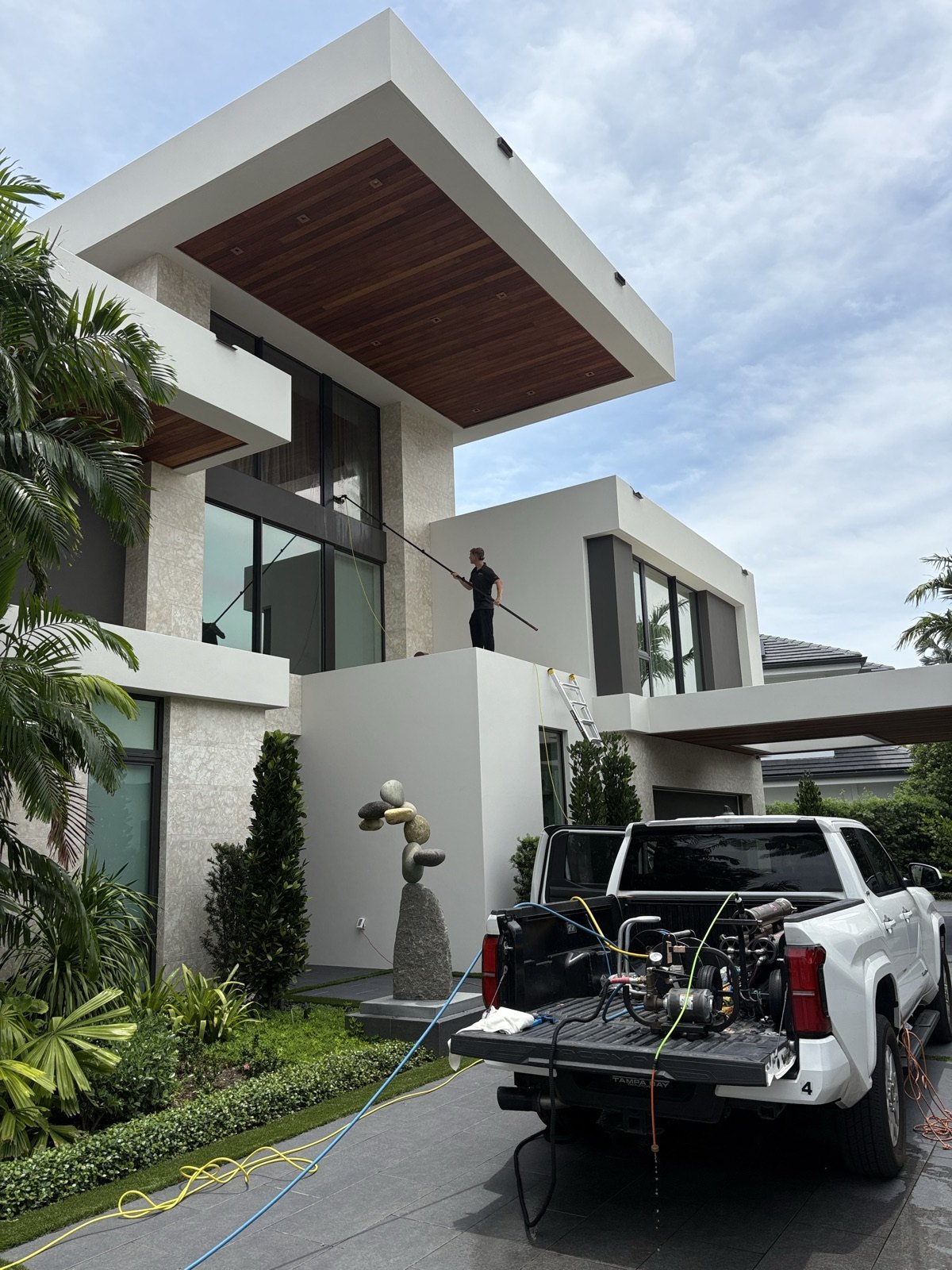 Fresh Frames truck with professional pure-water and soft-wash equipment parked in front of a modern luxury home in Boca Raton, with a crew member cleaning upper windows from a water-fed pole